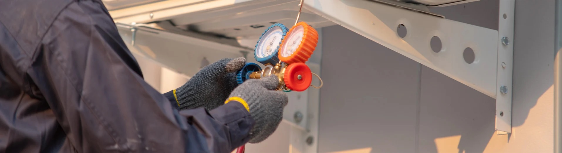 A worker wearing protective gloves checks the gauges on a device.